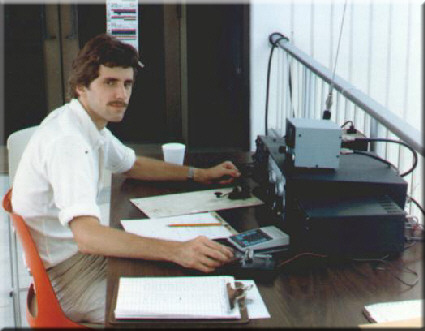 [Me during Amateur Radio Field Day in 1987.
Note the look of a dead-tired, irritated man,
who has been sitting all through the night,
listening to nothing but unending Morse Code
in his ear.  This is a desparate man.]